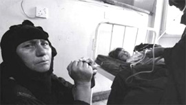 Photo by Andrew Stern - A woman sits by the bedside of her daughter Baghdad's Khadasiya Hospital June 10, 2003.