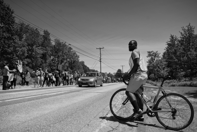 A bicycle escort stand guard as the group of more than 250 marchers approaches Waterbury, VT.