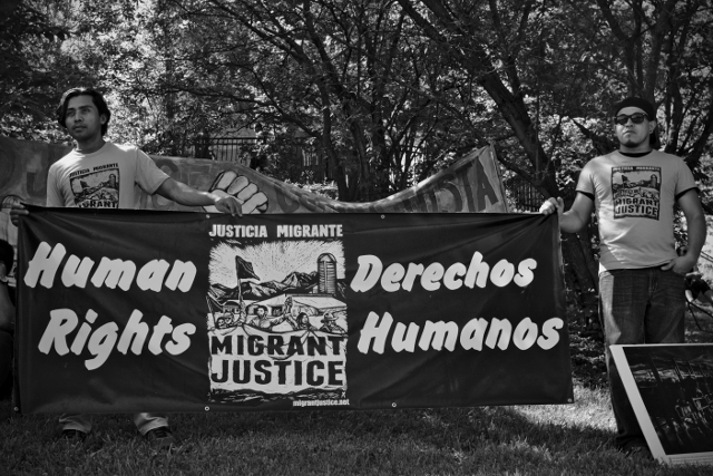Tired and overheated, marchers from Migrant Justice display banners demanding human rights and dignified working conditions outside the Ben & Jerry's factory in Waterbury, VT.