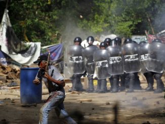 An injured protester flees as riot police use tear gas and batons to disperse a demonstration against the Tambor mining project at La Puya on May 23, 2014. (Reuters/Jorge Dan Lopez)
