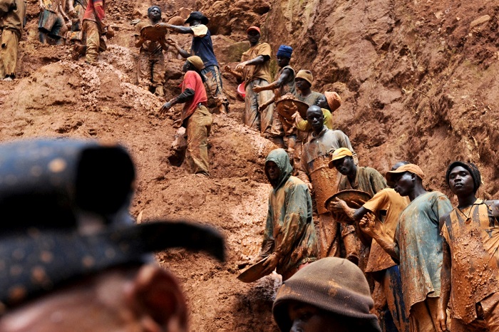 Mining workers stand on a muddy cliff as they work at a gold mine in northeastern Congo. (Photo: Lionel Healing/AFP/Getty Images)