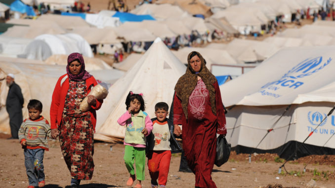 Syrian internally displaced people walk in the Atme camp, along the Turkish border in the northwestern Syrian province of Idlib, on March 19, 2013. Credit: Bulent Kilic/AFP/Getty Images