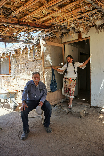 María de la Luz Villa Poblano, stands behind her husband, at the door to their house in the Santa Gertrudis Mission in an isolated area of the state of Baja California Sur, in northwestern Mexico. At 71, she is leading a battle for the recognition of the Cochimí indigenous people and their language. Credit: Daniela Pastrana / IPS