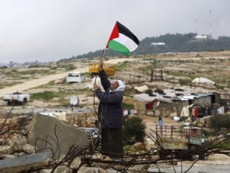 A Palestinian man hangs a Palestinian flag atop the ruins of a mosque during a snow storm in West Bank village of Mufagara, south of Hebron, in 2016. Credit: Mussa Qawasma/Reuters