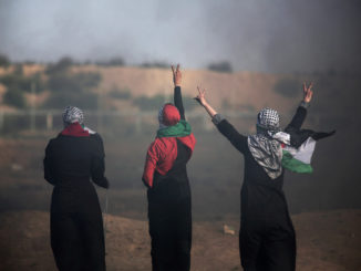 Palestinian women flash the peace sign in front of Israeli troops during a protest at the Gaza Strip’s border with Israel on June 1, 2018. (AP Photo / Khalil Hamra)