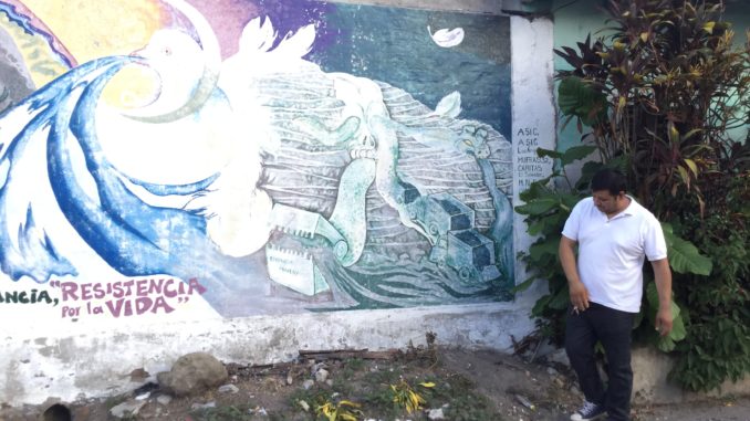 Miguel Rivera in front of anti-mining mural in his town in northern El Salvador