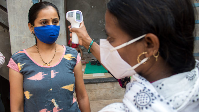 Trabajador acreditado de activista de salud comunitaria (Asha) que monitorea la temperatura de un miembro de la comunidad en el distrito de Kolhapur de Maharashtra