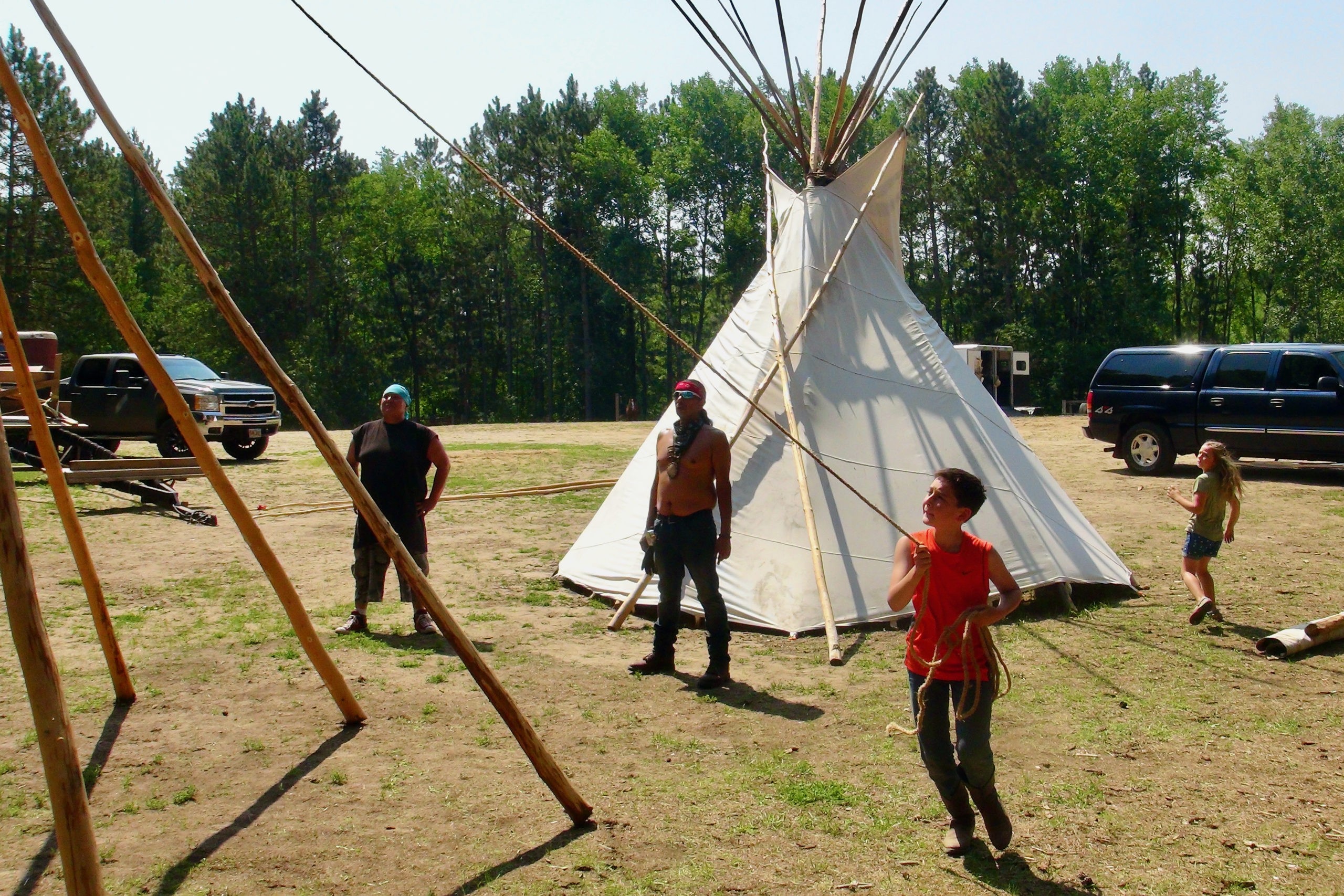 Jim Northrup III teaching youth how to erect a tipi at the Shell City Horse Camp. Sawyer tries his hand as a rope runner.
