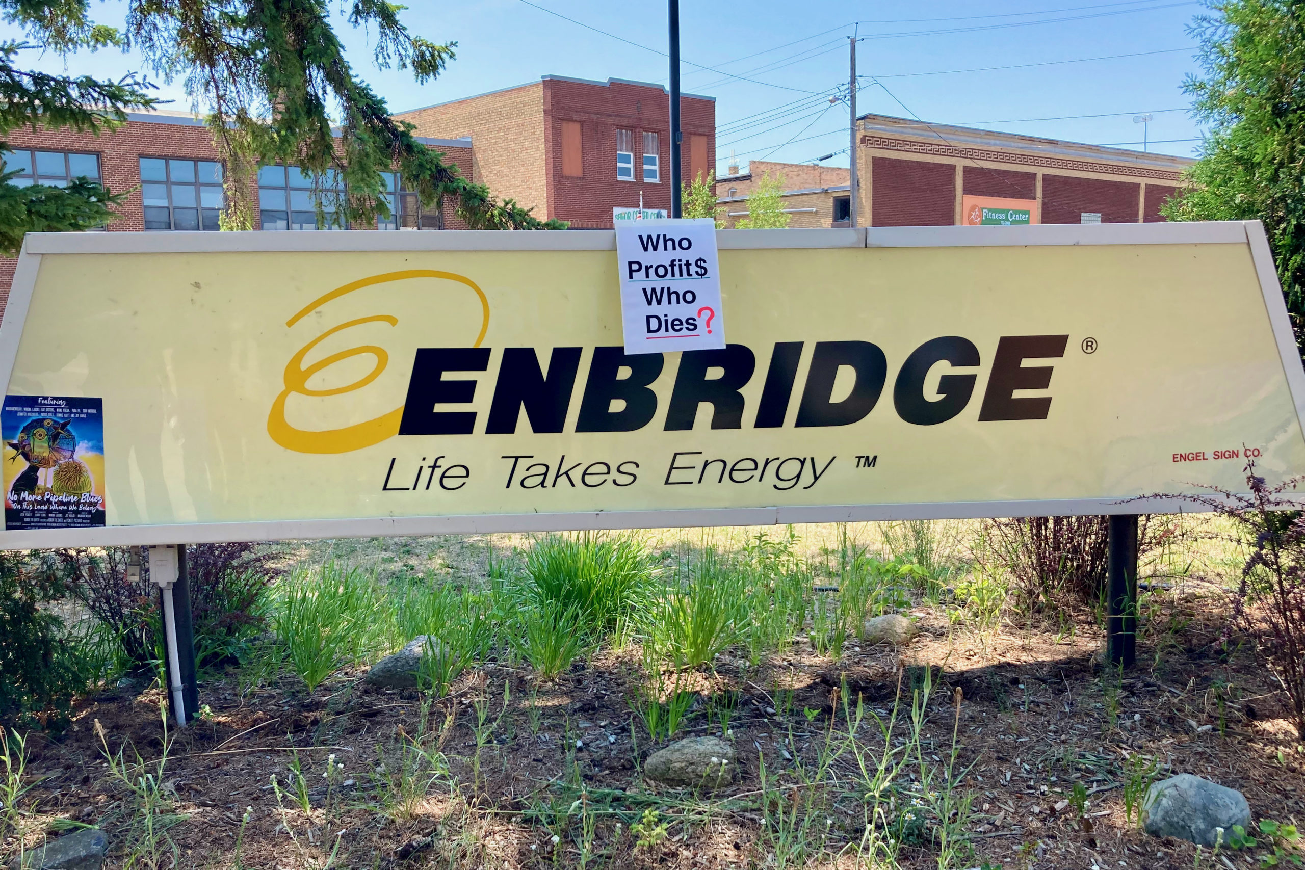 A sign left behind on the Enbridge entrance’s sign reads, “Who Profit$ Who Dies?”