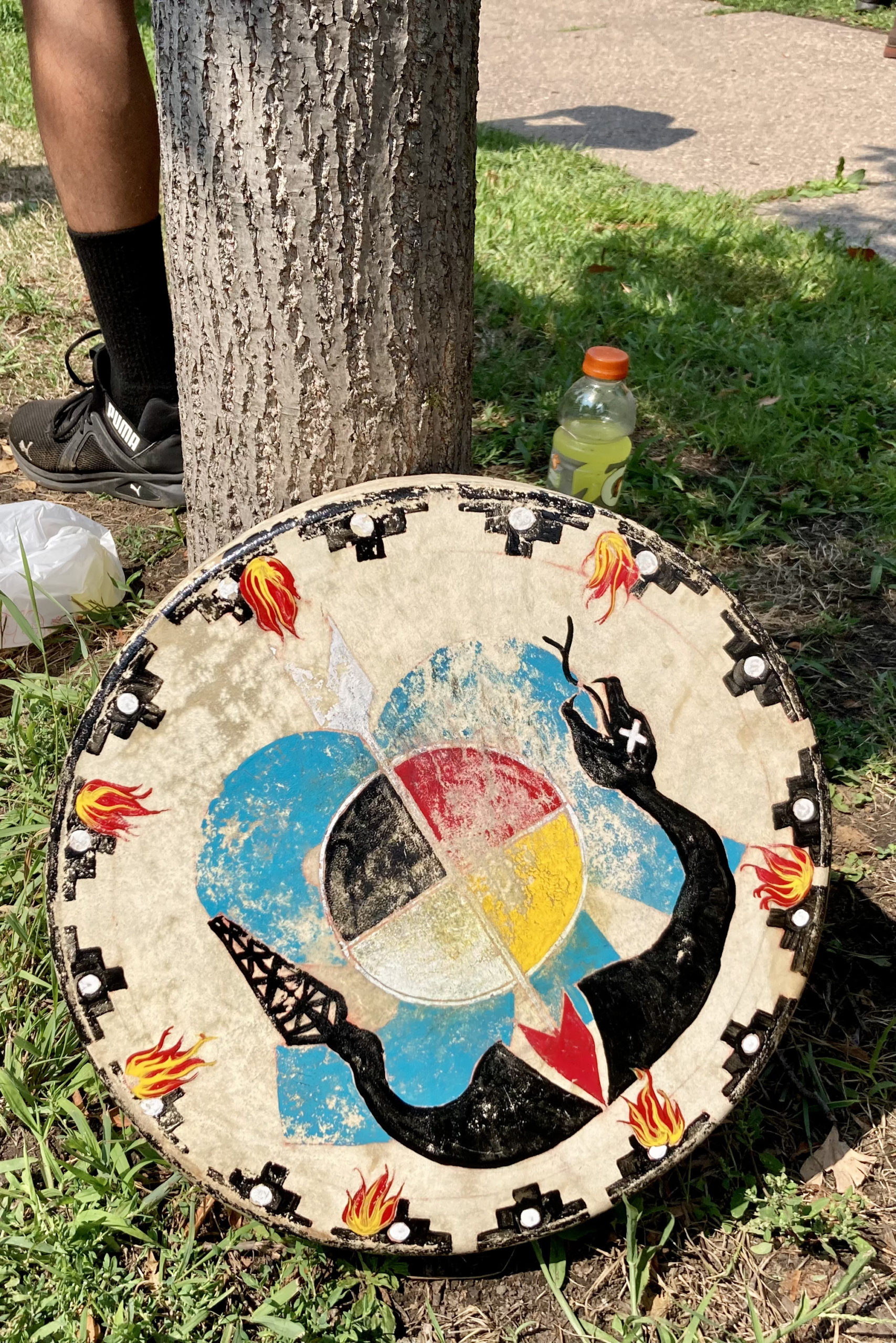 "Black Snake Killer" hand drum resting against a tree at the Martin Luther King Jr. Recreation Center in St. Paul MN at the end of the Treaty People Walk for Water. Dozens of walkers departed from Camp Firelight on August 7 and walked 259 miles to St. Paul, arriving on August 25, 2021. Walkers were joined by others at the recreation center for the final mile and a half walk to the State Capitol. They marched in silence in honor of the thousands of children's remains found in residential boarding schools over the summer, and for all the missing and murdered Indigenous relatives. https://www.stopline3.org/events/treatypeoplewalk