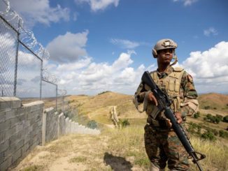A Dominican soldier stands by a 118-mile border wall the Dominican Republic built to keep out Haitian migrants / credit: La Prensa Latina