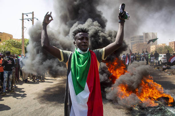 Burning rubbish and a protester wearing a Sudanese flag during a protest in the streets of Khartoum, Sudan, following the October 25 coup / credit: Revolutionary masses of Sudan