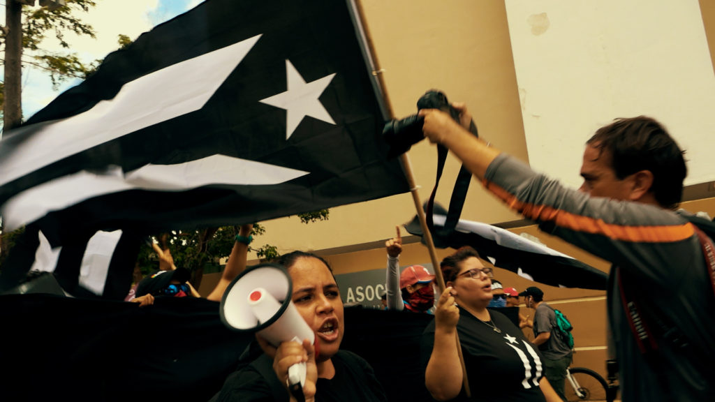 Screenshot from documentary "Drills of Liberation," in which Jocelyn Velásquez speaks into a bullhorn during a march in San Juan, Puerto Rico / Published with permission from the director, Juan Carlos Dávila