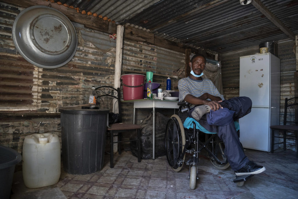 Zachariah Mokhothu inside the home he shares with his mother in the South African township of Kutlwanong. In his 15-year mining career, he got injured and developed tuberculosis before his paralysis / credit: Ihsaan Haffejee / New Frame
