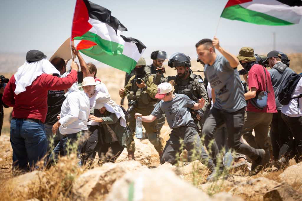 Israeli military personnel push a U.S. solidarity activist / credit: Emily Glick