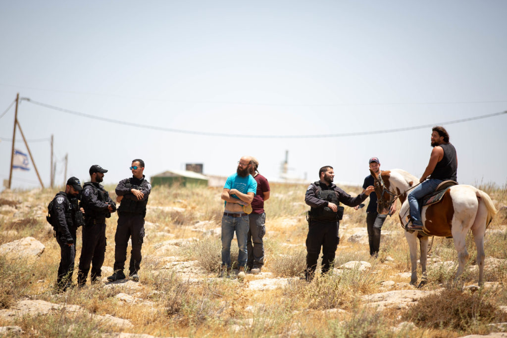Israeli military personnel on June 10 mingle with settlers from the colony of Mitzpeh Yair / credit: Emily Glick