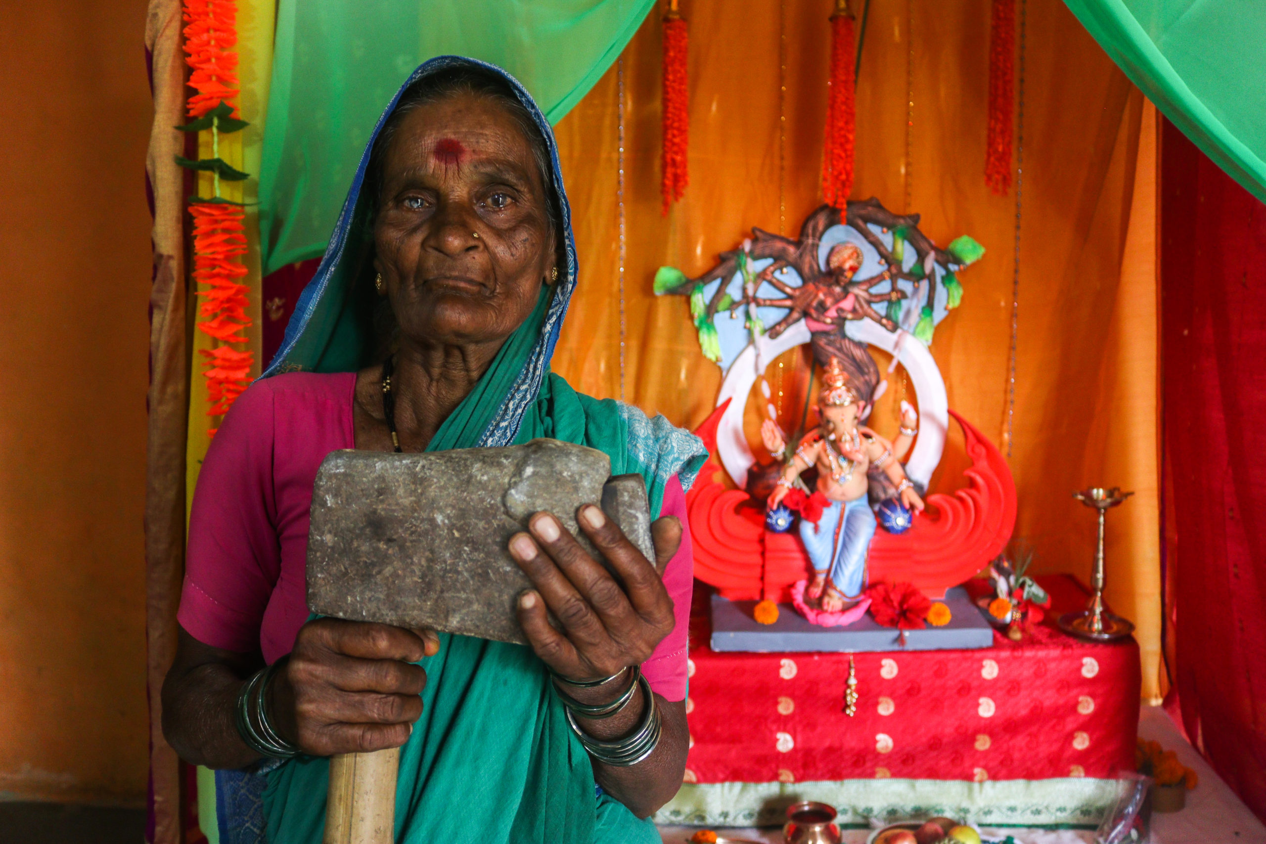Kastura Chougule holding her son’s sledgehammer, which remains his last memory / credit: Sanket Jain