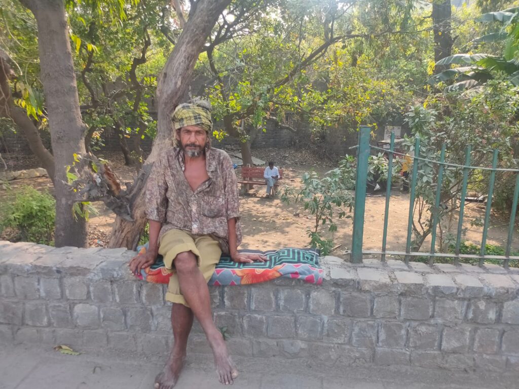 Yamuna Pushta resident Arun Kumar Jha sits on a footpath across from Ring Road in Delhi / credit: Parva Dubey